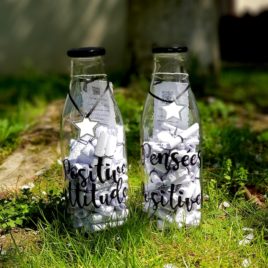 Présentation de deux bouteilles en verre remplies de 60 pensées positives. Une avec l'inscription : "Positive attitude" et l'autre "Pensées positives"